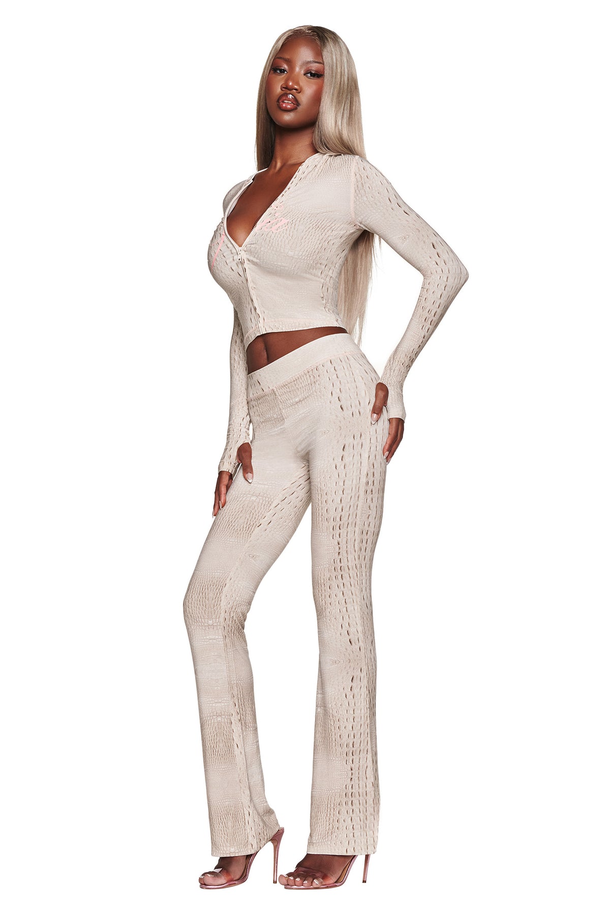 A woman with long blonde hair poses in the I.AM.GIA BLARE HOODIE - HOT CROC, styled with high heels and standing against a white background.
