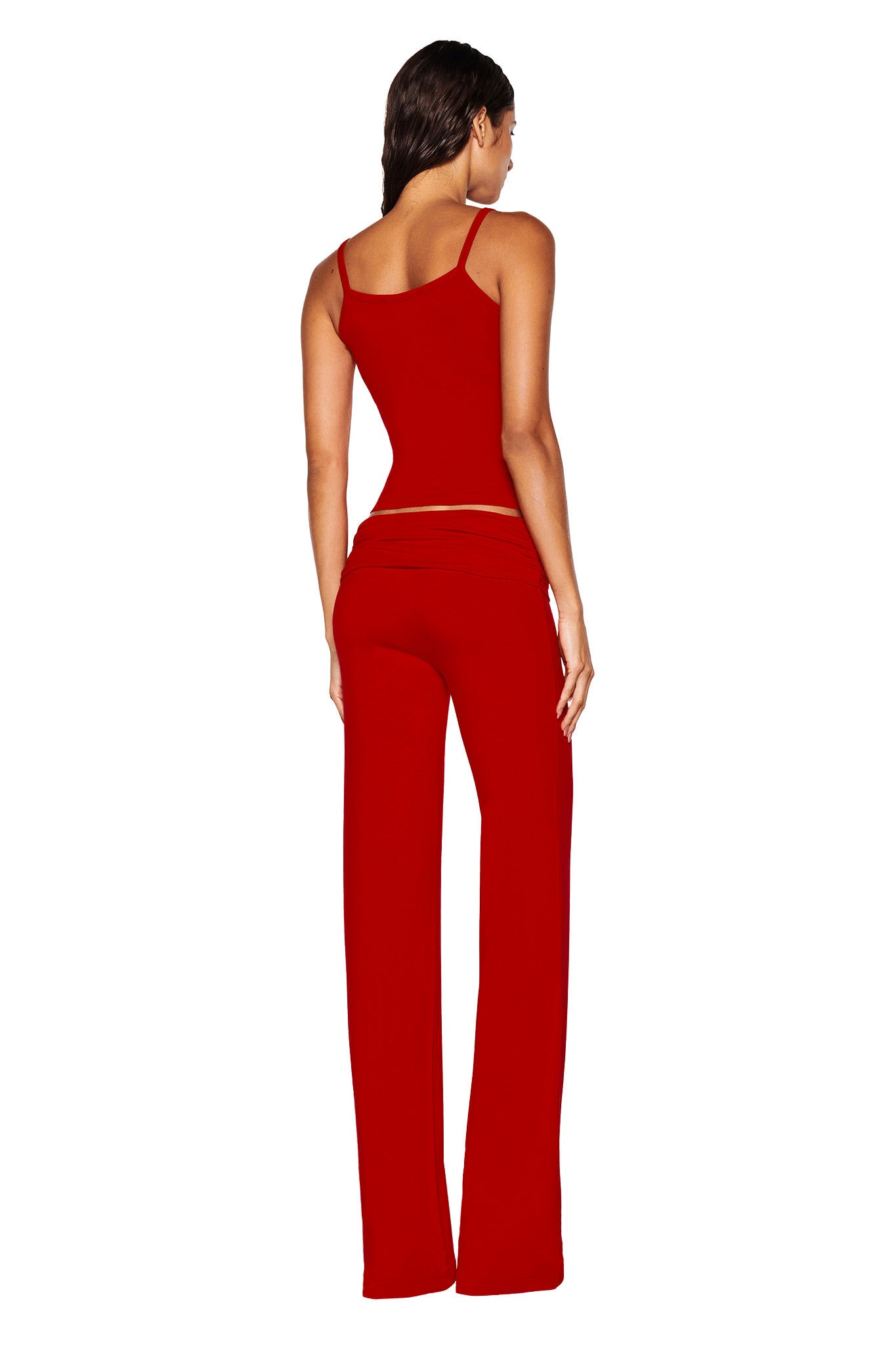 A person with long hair is wearing the ERIN TOP - RED by I.AM.GIA, showcasing delicate red lace trim, along with matching red pants. They are standing and facing away from the camera against a plain white background.