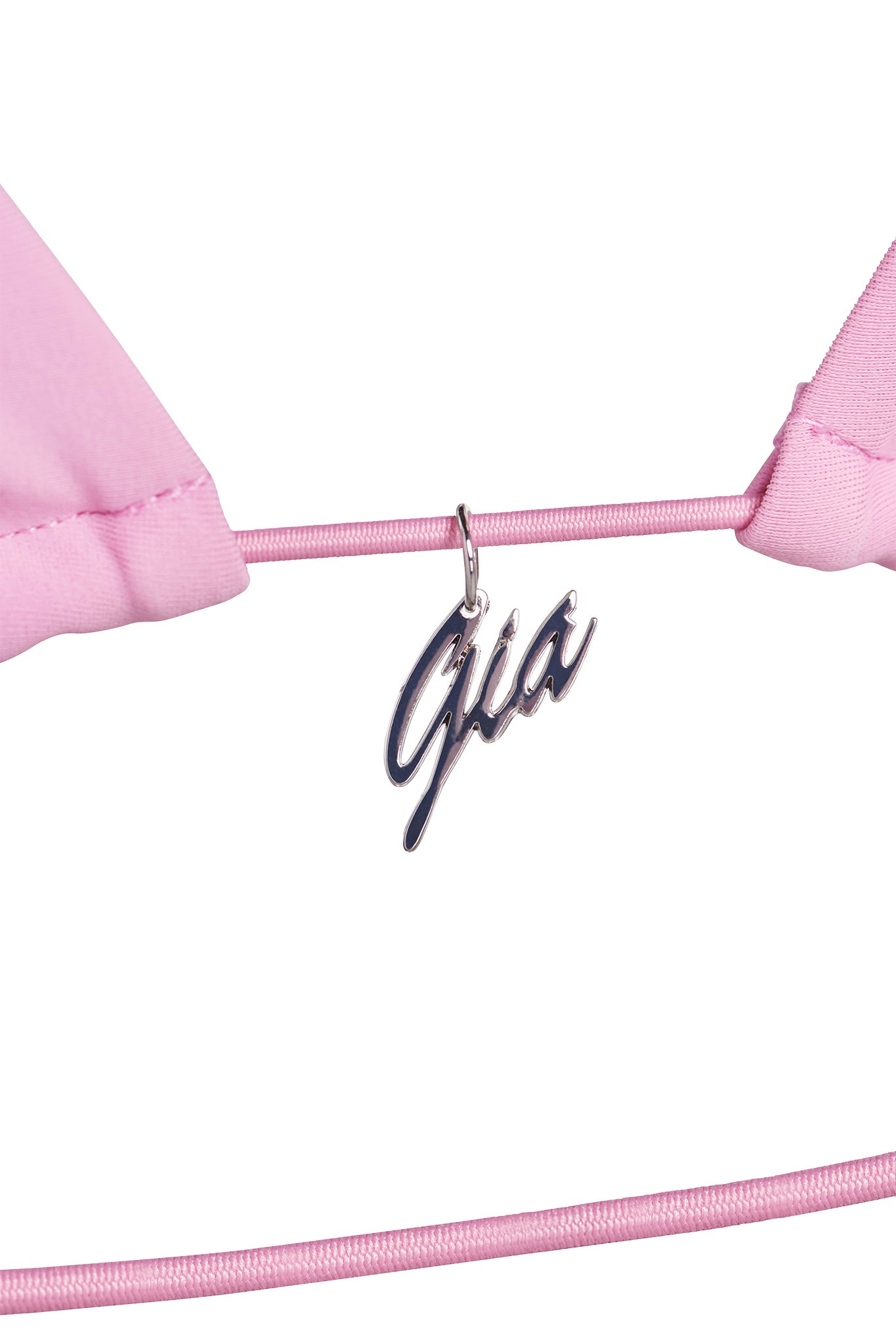 Close-up of the BAMBI BIKINI TOP - PINK : BUBBLEGUM from I.AM.GIA, featuring a metallic charm in the center with script text reading "Gia." The matching pink straps complement the overall color. The background is plain white.