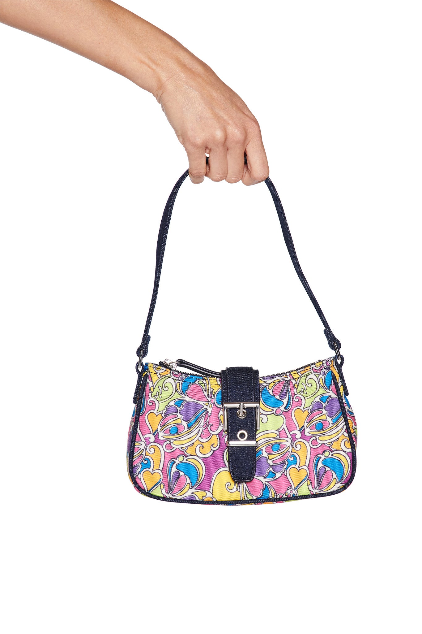 A hand holds the I.AM.GIA LILLIA BAG - TROPICAL BUTTERFLY BLOOM, a small vibrant handbag with a bold floral print, black strap, and black buckle detail, displayed against a white background.