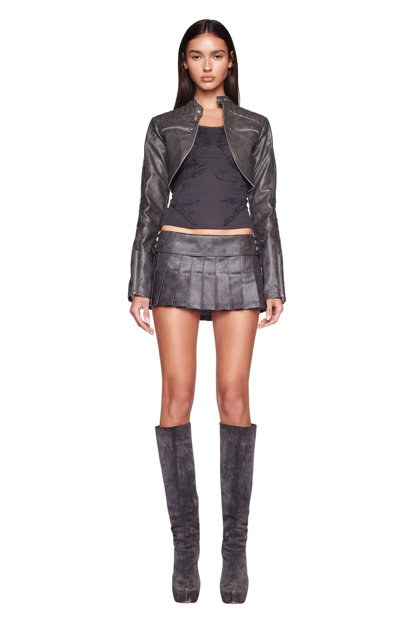 A woman stands facing forward, wearing a fitted leather jacket, a black top, and the I.AM.GIA KARI SKORT in charcoal grey with lace-up detailing. She completes the look with knee-high leather boots. Her long, straight hair cascades down as she maintains a neutral expression against the white background.