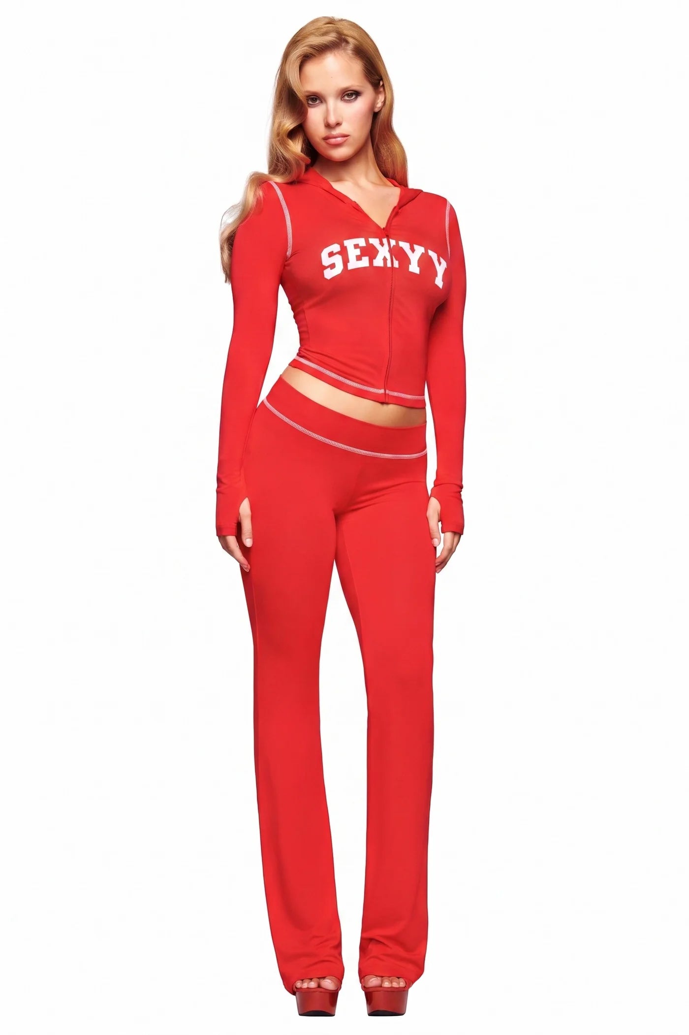 A woman with long blonde hair stands against a white background, wearing the I.AM.GIA X SEXYY RED BLARE HOODIE in red with "SEXY" in white lettering and matching red pants.